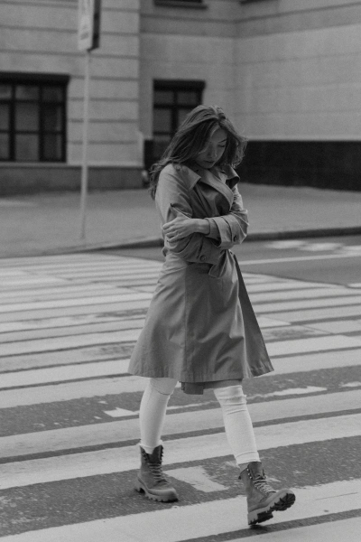 Black and white of woman in coat crossing a crosswalk