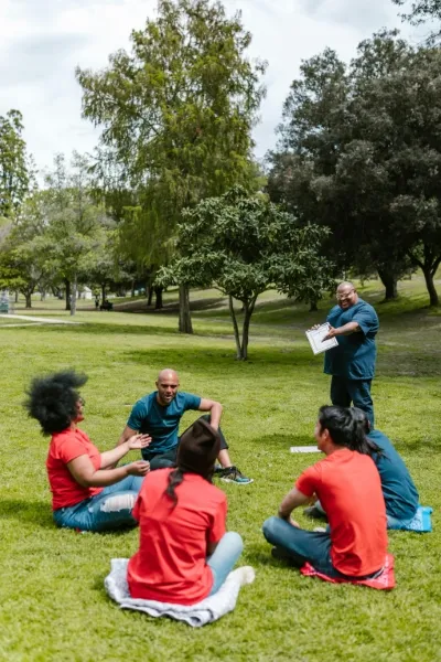 Group of people sitting in a circle on the grass in a park